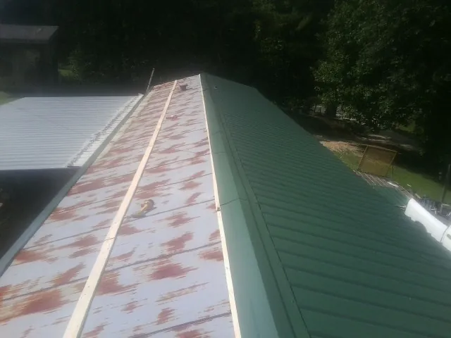 Old rusted panels beside newly installed green metal roofing — Wind Damage Roof Repair by Roofing Brothers in Vernalis