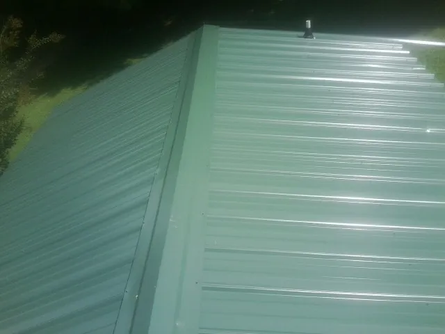 New green metal panels meeting at the ridge of a roof — Flat Roof Repair work by our crew in Vernalis