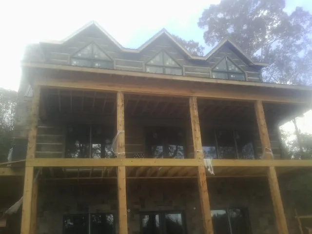 Dormers and porch framing on a large log home under construction — Roof Coating work by our crew in Vernalis