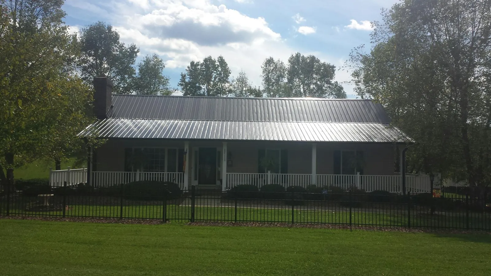 Gray metal roof on a brick ranch with a full width front porch — Gutter Guard Installation work by our crew in Vernalis