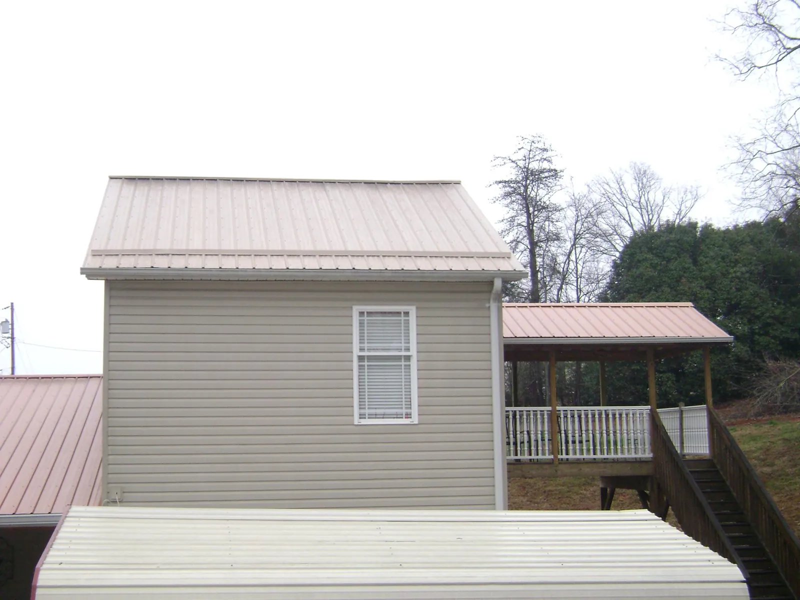Tan metal roofs on a two story addition and attached porch, from a Roof Replacement job in Vernalis