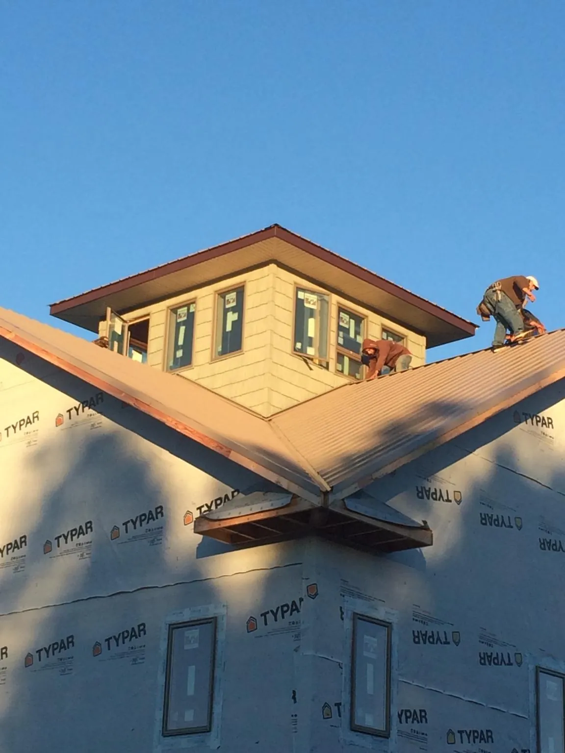 Roofers working around a rooftop cupola on a new metal roof at sunset — Roof Waterproofing in Vernalis by Roofing Brothers